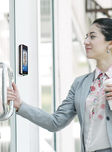 Woman using facial recognition to unlock secure office door with Suprema BioStar Air BioStation 3 reader